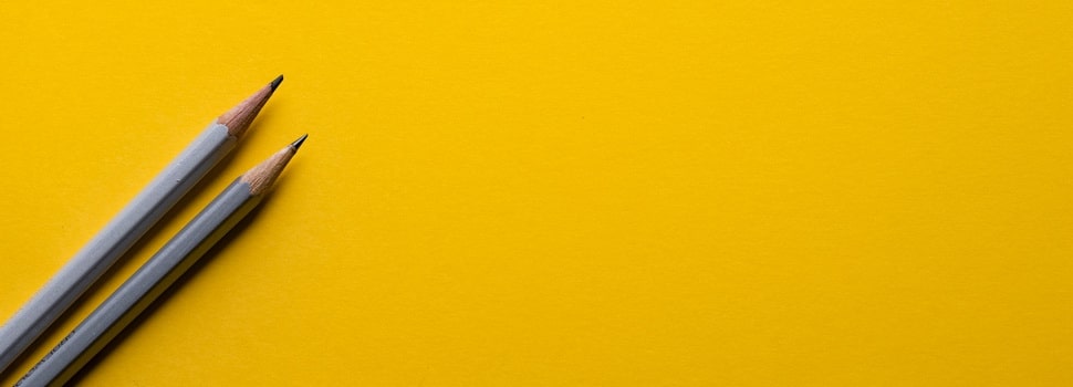 two pencils on a yellow paper background