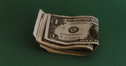 several folded dollar bills lying on a green surface
