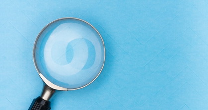 magnifying glass on light blue wallpaper