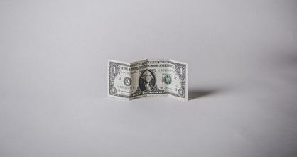 single dollar bill standing up on a grey and bleak background