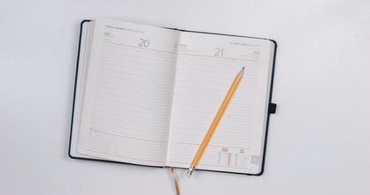 a monthly planner and pencil on a white surface