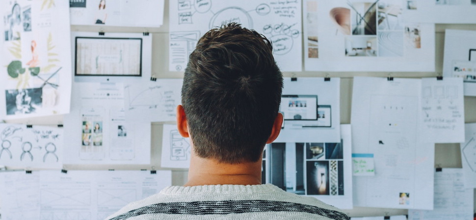 man looking at wall covered with different documents