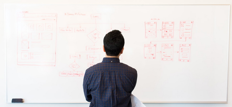 man looking at sitemap drawings on whiteboard