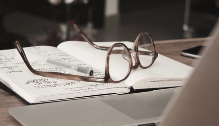 glasses with grey rims lying on a notebook