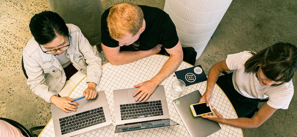 people sitting collectively around a round table and working on their laptops