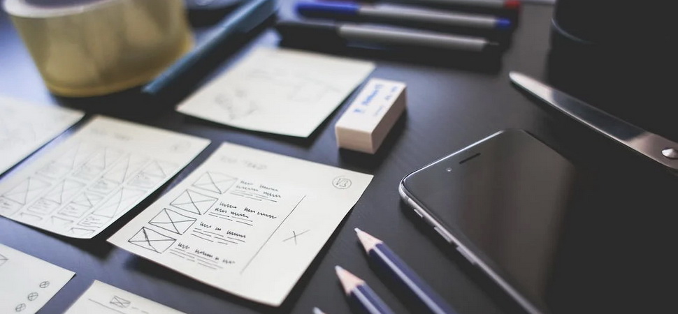 desk covered in sheets of paper and stationary used for drawing up website scoping plans