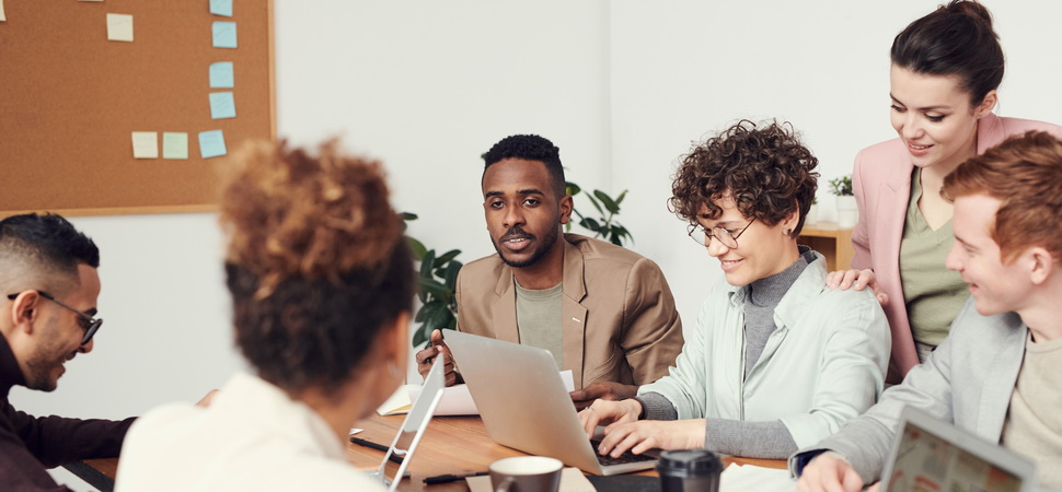 group of multicultural men and women sitting around a desk at the office and discussin work